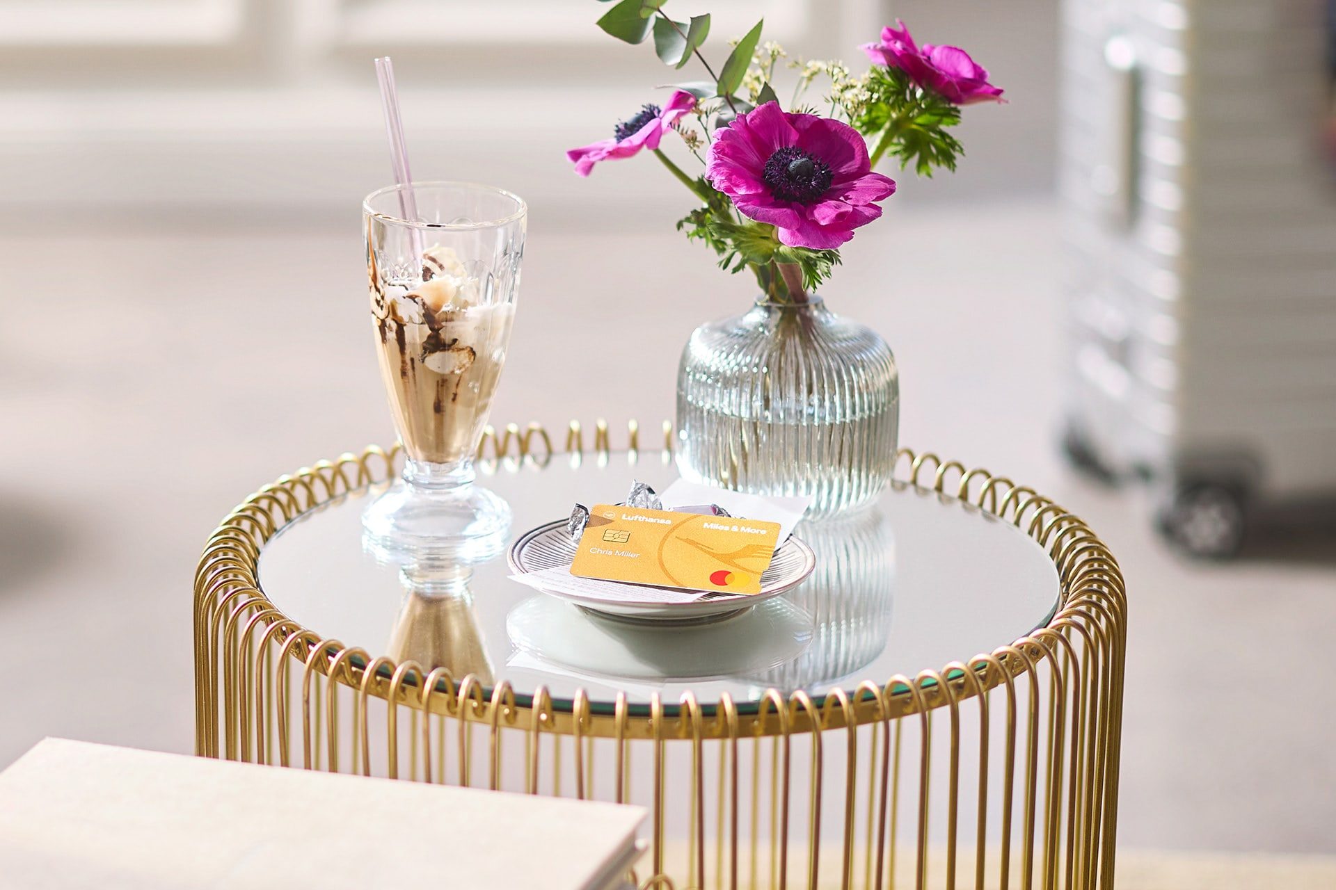 Gold Credit Card liegt auf einem kleinen Tisch, daneben ein Becher mit Eis 