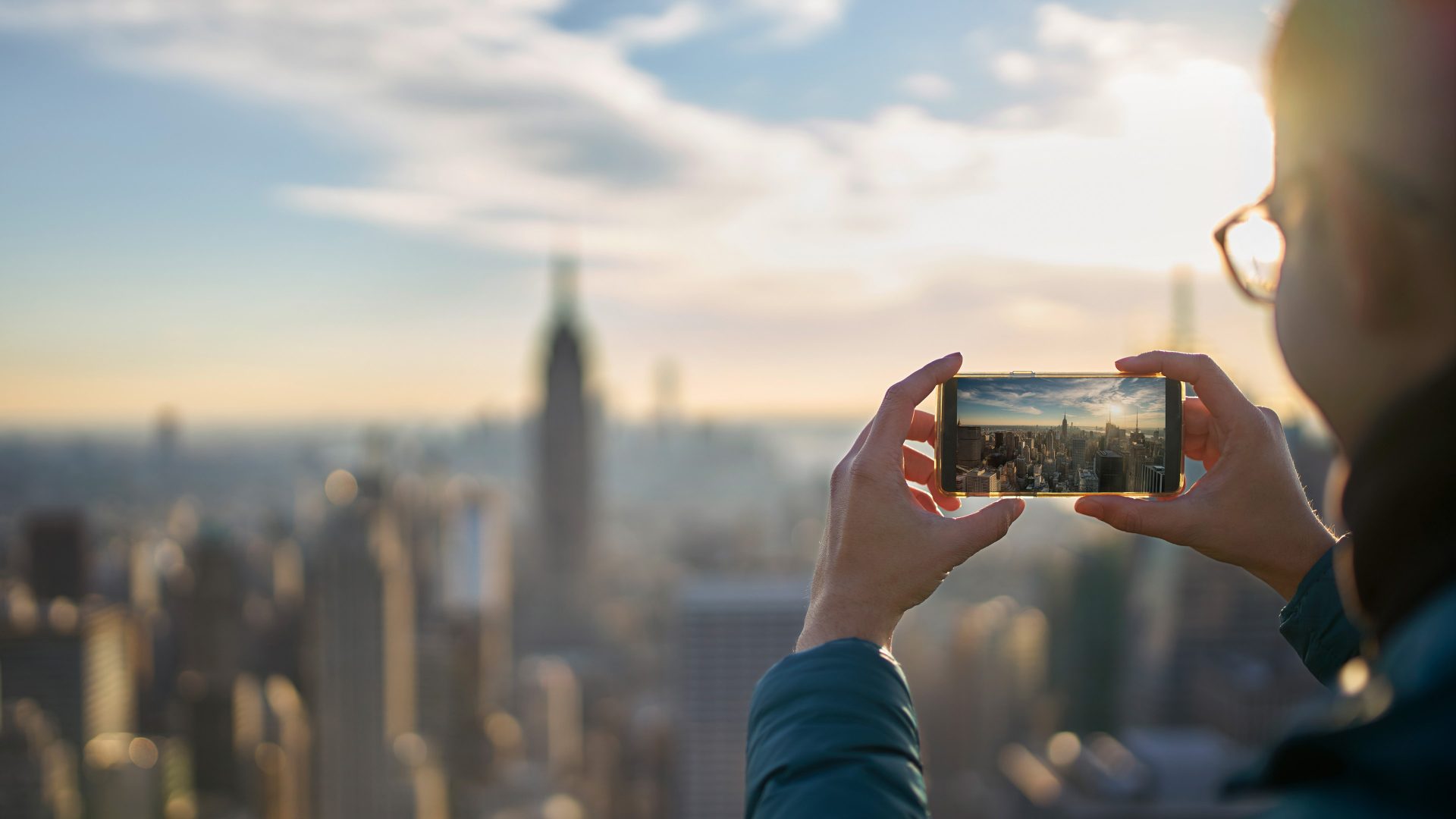Mann fotografiert die Skyline von NewYork mit seinem Handy. 
