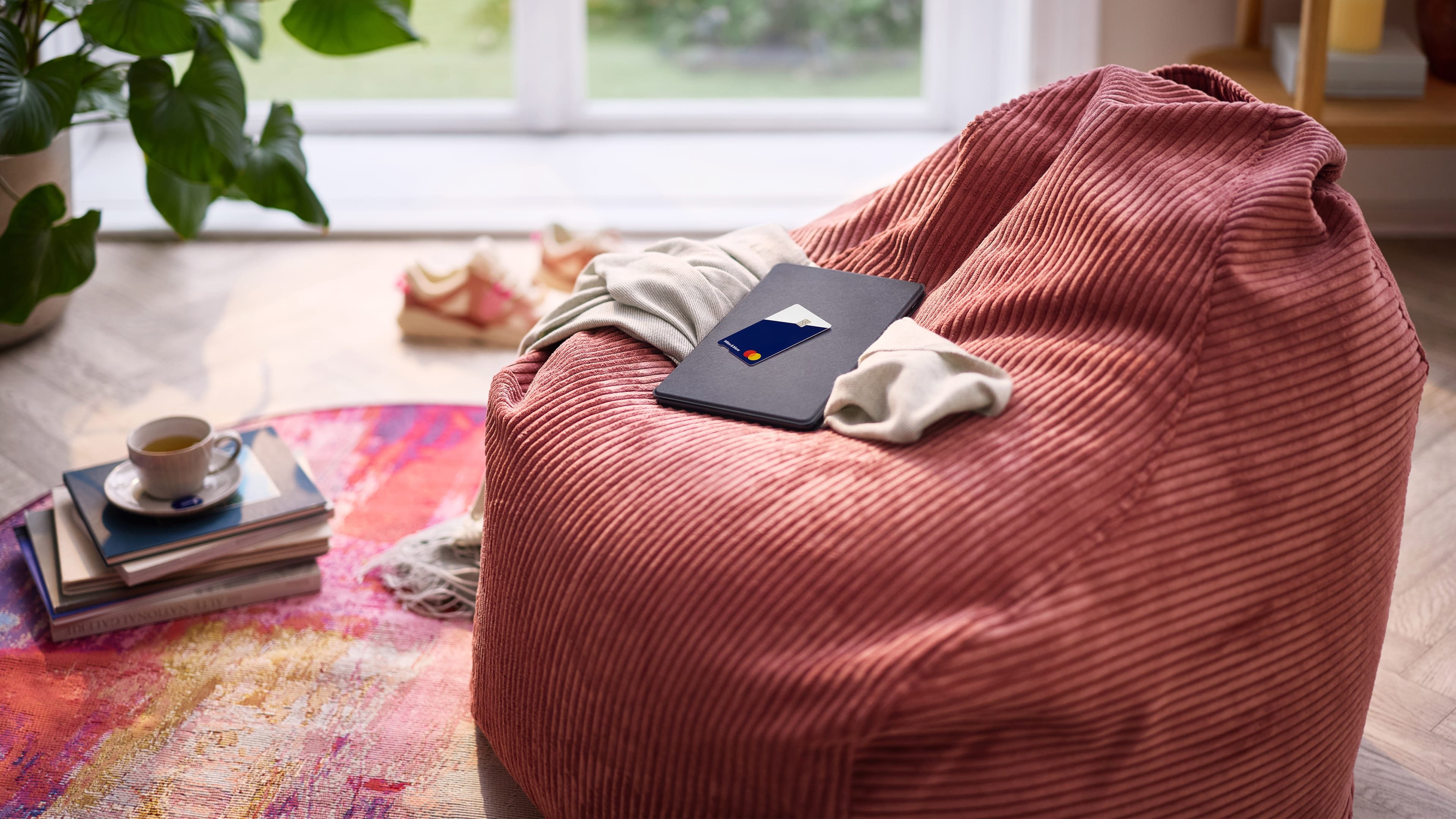 MyFlex Credit Card liegt auf Laptop im Wohnzimmer mit Turnschuhen im Hintergrund 