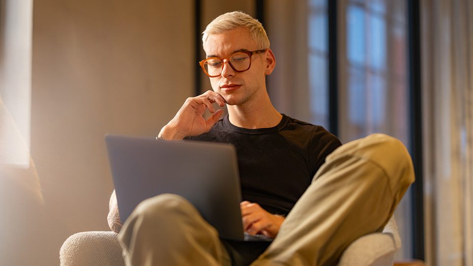 Person arbeitet mit einem Laptop in einem Sessel in einem modern gestalteten Innenraum 